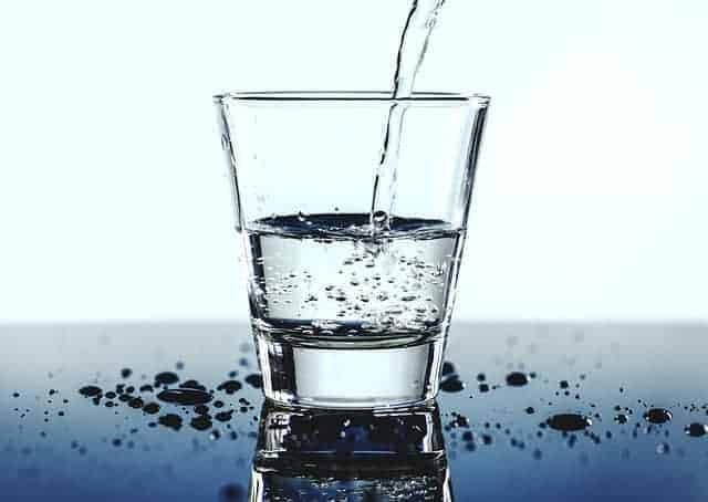 Clear Glass of water with straw with blue backdrop