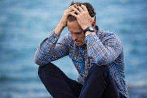 Feeling Sad Guy holding his head in frustration by water