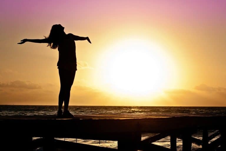 Learn How to Meditate Silhouette of women with arm open at beach in sunset