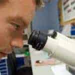 Male Lab worker looking into microscope